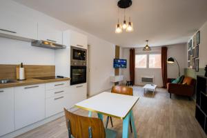 a kitchen and living room with a table and chairs at Hesdin Appart Holidays 2 in Hesdin