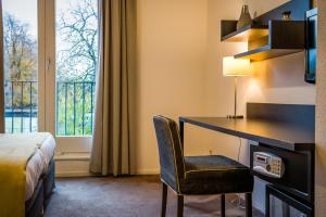 a hotel room with a desk and a bed and a window at Parkhotel Auberge Vincent in Nuenen