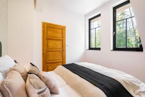 a bedroom with a bed and two windows at Horský apartmán Kuba in Bedřichov