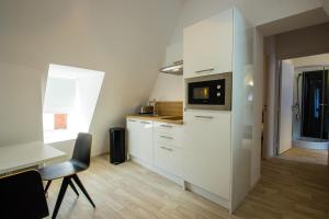 a kitchen with white cabinets and a table and a microwave at Hesdin Appart Holidays 4 in Hesdin