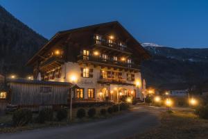 a large wooden building with lights in the night at Schlosswirt Chalets & Apartments in Großkirchheim
