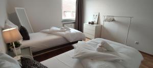 a bedroom with two beds with white sheets and a mirror at Liberty Hafen - Arbeiten, Ankommen, Wohlfühlen in Bremerhaven