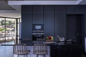 a kitchen with black walls and wicker chairs at Elounda Olivia Luxury Villa Spinalonga View in Elounda