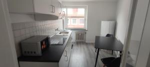 a small kitchen with a microwave and a stove at Liberty Hafen - Arbeiten, Ankommen, Wohlfühlen in Bremerhaven