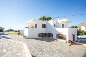 a white house with a stone driveway at Christine Beachside Villa Pefkos in Pefki