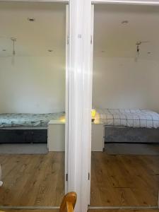 a room with two beds and a mirror at Compact single room A near Heathrow with 24 hour buses to all terminals in Feltham