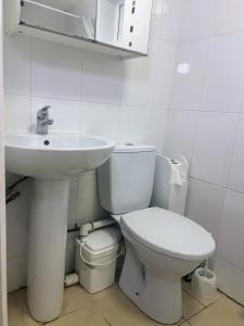 a white bathroom with a toilet and a sink at Compact single room A near Heathrow with 24 hour buses to all terminals in Feltham