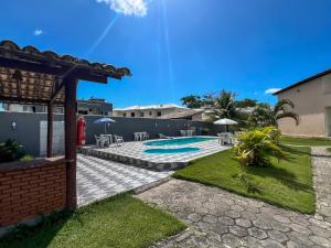 a backyard with a swimming pool with tables and chairs at Hotel Porto das Ancoras in Porto Seguro
