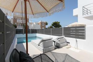 a patio with chairs and an umbrella and a swimming pool at Amelia villas Naxos in Naxos Chora