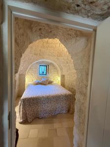 a bedroom with a bed in a stone wall at Trulli Clematis with Pool in Selva di Fasano +51 photos
