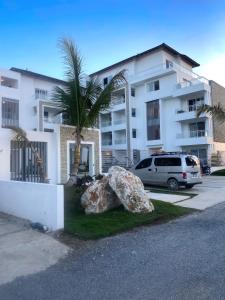 a car parked in front of a building with a palm tree at Apartamento Vacacional Coral Azul - SBH in Bayahibe