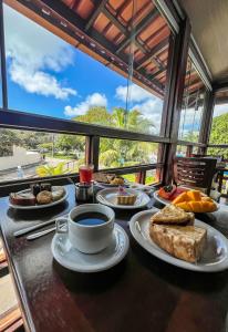 a table with plates of food and a cup of coffee at Hotel Porto das Ancoras in Porto Seguro