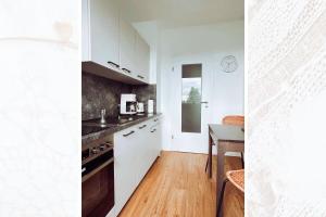 a kitchen with white cabinets and a wooden table at Käferhain, App 135 in Groitzsch +17 photos