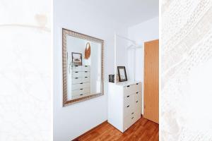 a white bedroom with a mirror and a dresser at Käferhain, App 134 in Groitzsch +21 photos
