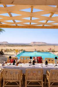 a table and chairs in front of a blue pool at Soléi Desert Retreat in Siwa