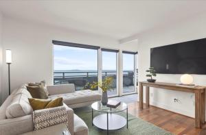 a living room with a couch and a flat screen tv at Luxury, ocean view Condo with deck and indoor pool in Seattle