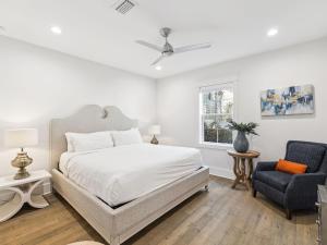 a white bedroom with a bed and a chair at CaSEAta by 30A Escapes in Rosemary Beach