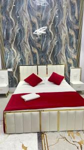 a white bed with red pillows and a wall at Klass in Taraz