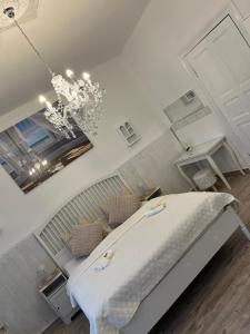a white bedroom with a bed and a chandelier at NordseeNest Varel in Varel