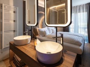 a bathroom with two white sinks and a couch at Corones Suites - Dolomites Residence in Valdaora +72 photos