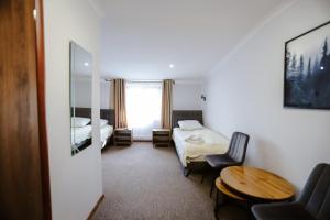 a hotel room with a bed and a table and chair at Hotel Lubaczów Hotel Restauracja u Dina in Lubaczów