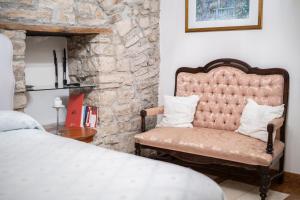 a bedroom with a bed and a chair next to a stone wall at La Cantina del Convento in Potenza