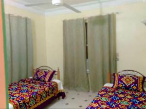 a bedroom with two beds and a window with curtains at Tetas Villa in Naj‘ al Maḩaţţah