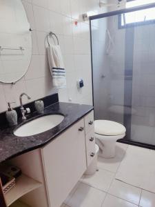 a bathroom with a sink and a toilet and a mirror at Apartamento Completo I Suíte Casal in Guarapari +8 photos