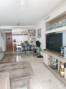 a living room with a couch and a television at Apartamento Completo I Suíte Casal in Guarapari