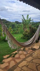 a hammock on a patio with a view of a field at Pousada e Camping Caldeirão Furado in São Thomé das Letras