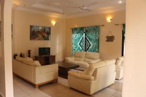 ein Wohnzimmer mit zwei Sofas und einem Fernseher in der Unterkunft Londoninnn Brusubi Heights 4U in Brusubi