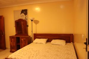 ein Schlafzimmer mit einem Bett und einer Kommode mit Lampe in der Unterkunft Londoninnn Brusubi Heights 4U in Brusubi