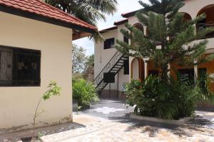 ein Haus mit einer Palme im Hof in der Unterkunft Londoninnn Brusubi Heights 4U in Brusubi