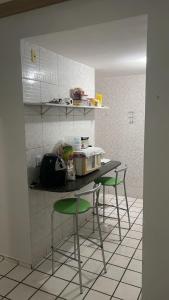 a kitchen with a counter with three green chairs at Solares Residence in Teresina