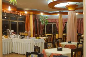 a dining room with white tables and chairs and windows at Hotel Condeza in La Paz