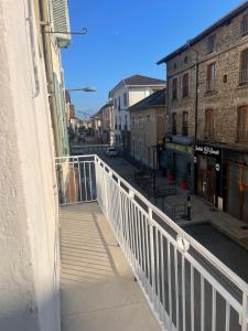 ein Balkon mit weißem Geländer an einer Stadtstraße in der Unterkunft Station in Saint-Étienne-de-Saint-Geoirs