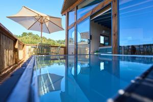 a swimming pool with an umbrella and a house at Loica in Pichilemu