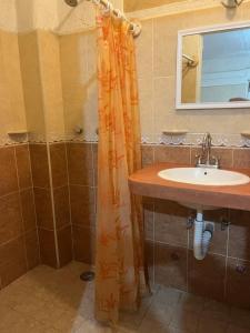 a bathroom with an orange shower curtain and a sink at Hotel Diana cazadora in Zihuatanejo
