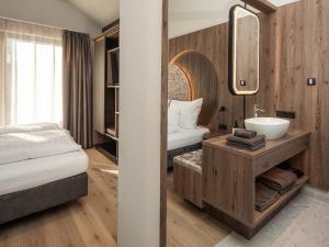 a bathroom with a bed and a sink in a room at Corones Suites - Dolomites Residence in Valdaora