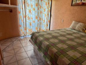 a bedroom with a bed and a window with curtains at Hotel Diana cazadora in Zihuatanejo