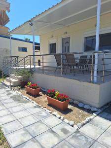 a porch with three pots of flowers on a house at Sea Breeze House in Paralia Katerinis +9 photos