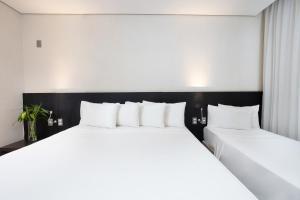 two large white beds in a hotel room at Hotel Park Tower Savassi by Nacional Inn in Belo Horizonte +101 photos
