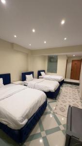 a row of four beds in a room at Atlantis pirámides view Inn in Cairo