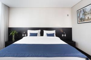 a bedroom with a large bed with blue sheets at Hotel Park Tower Savassi by Nacional Inn in Belo Horizonte
