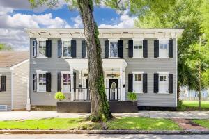 a white house with black shutters and a tree at Charming Historic Condo with Pool in Savannah