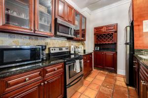 a kitchen with wooden cabinets and a stove top oven at Charming Historic Condo with Pool in Savannah