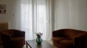ein Wohnzimmer mit zwei Stühlen und einer Vase auf einem Tisch in der Unterkunft Central in Chalkida