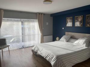 a bedroom with a large bed with a blue wall at Chez Marie et Angel in Autun