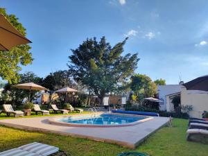 a swimming pool in a yard with chairs and umbrellas at La Casona Minera in Mineral de Pozos
