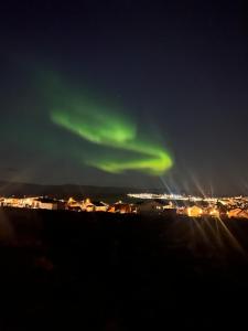 an aurora in the sky over a city at night at Nyoppusset leilighet i Vadsø in Vadsø +3 photos